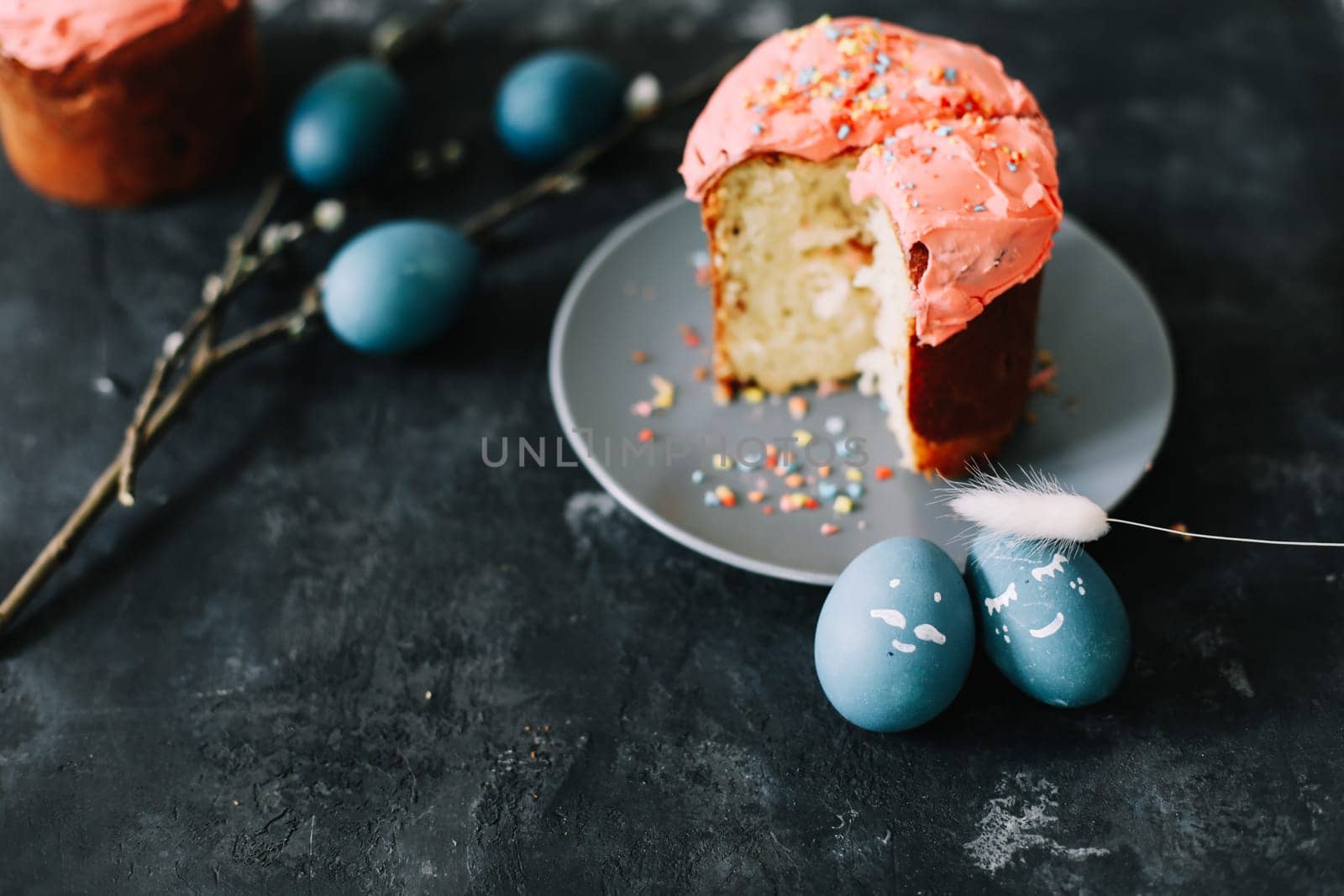 Plate with tasty Easter cake, eggs and willow branches on dark background. High quality photo