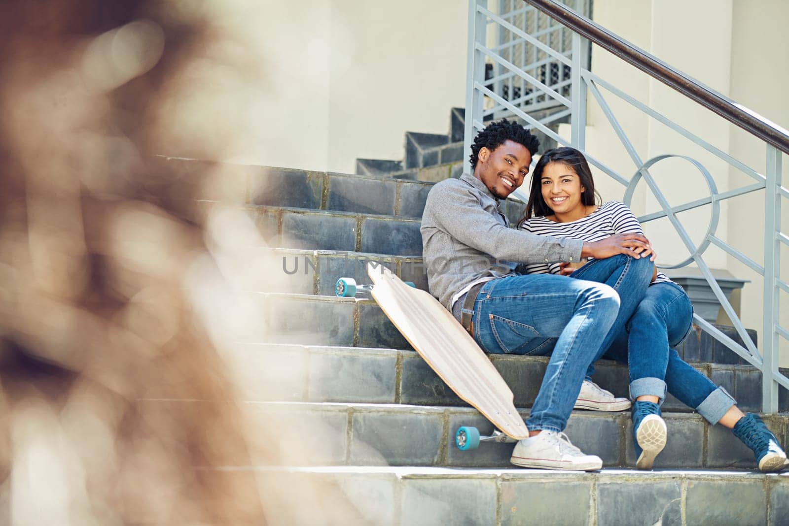 Couple, happy and skateboard while sitting on stairs with hug, love and romance in city sunshine. Black couple, urban happiness and outdoor with skater, embrace and romance on steps in San Francisco.