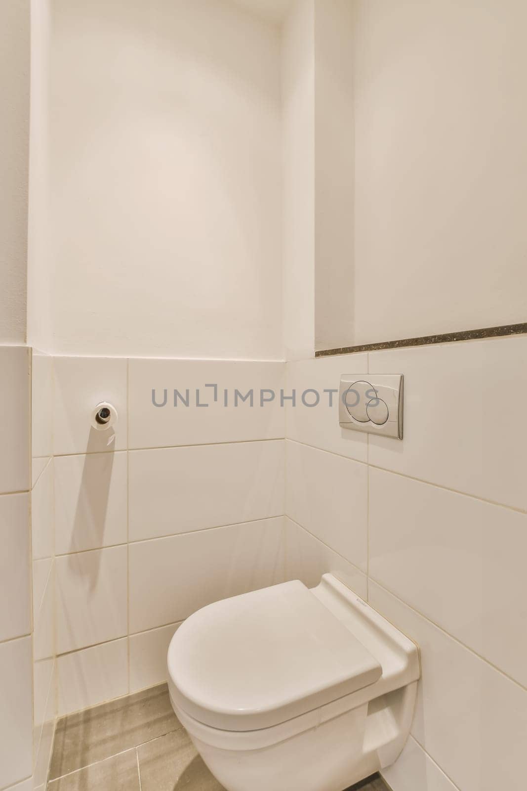 a white toilet in the corner of a bathroom with tile on the floor and walls, it is very clean