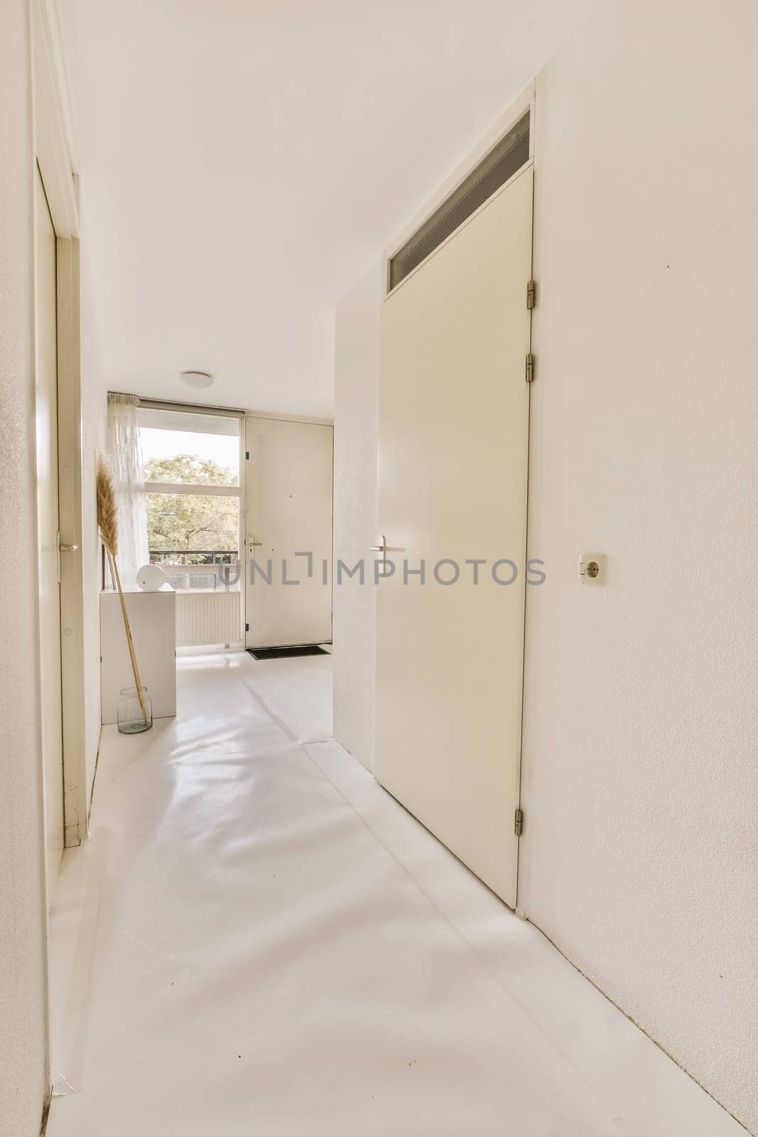 a white hallway with a door and a mop by casamedia