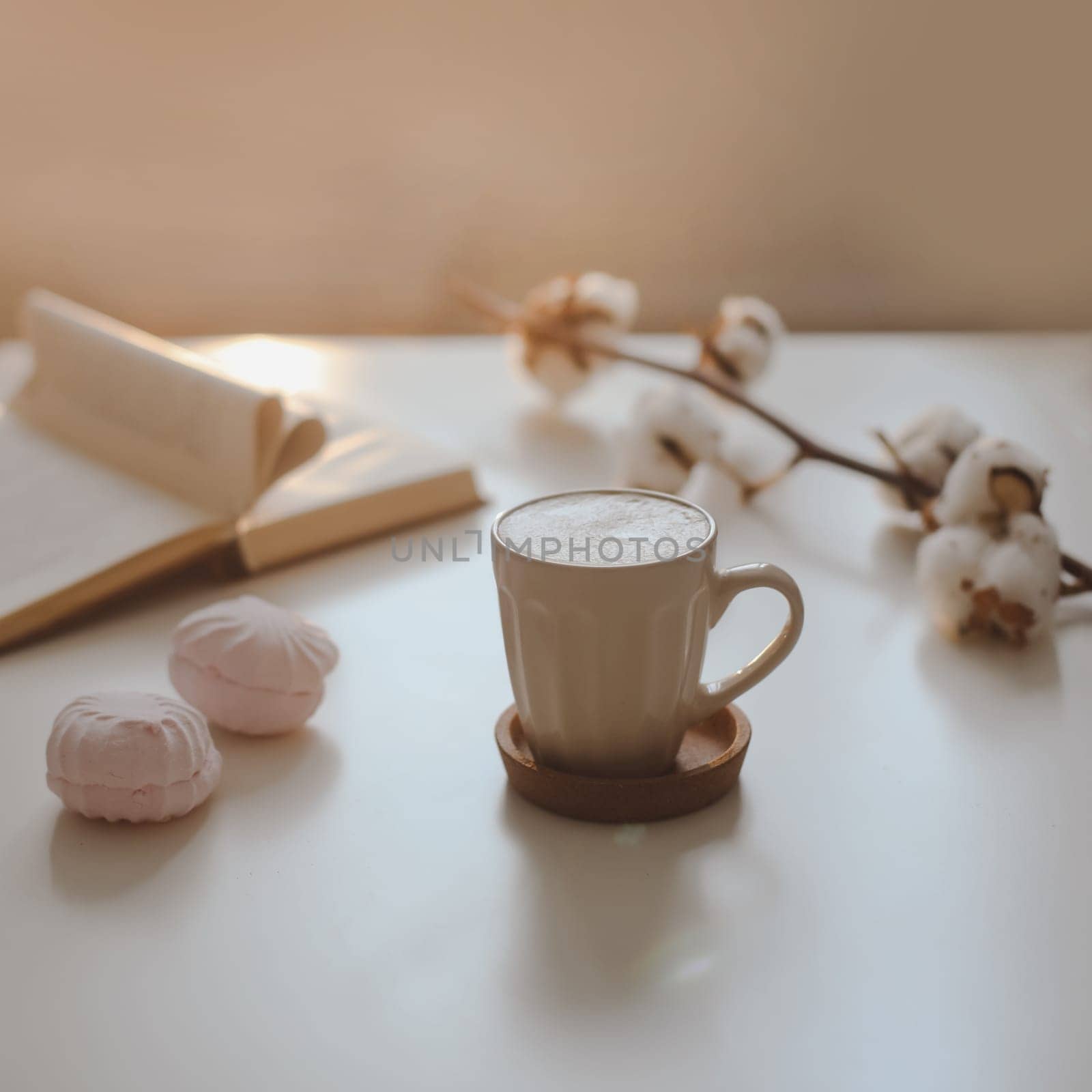 coffee cup, flower, candle and a book on a white table background top view. minimal home interior decor by paralisart