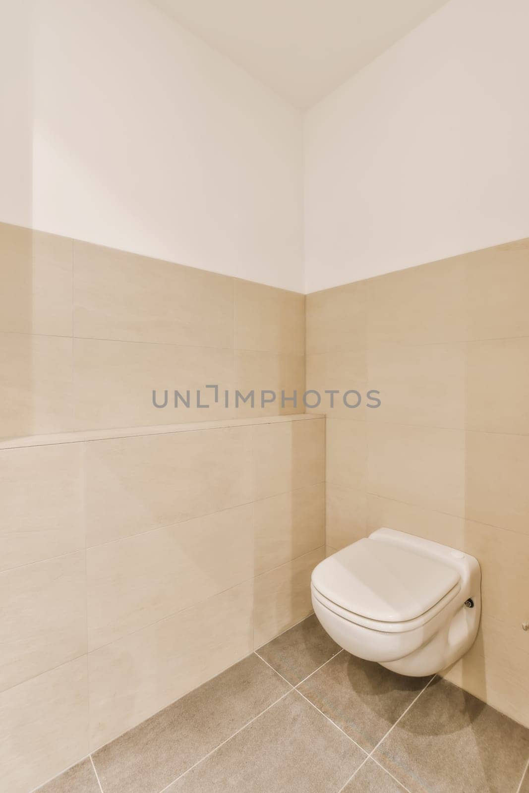 a white toilet in a bathroom with beige tiles by casamedia