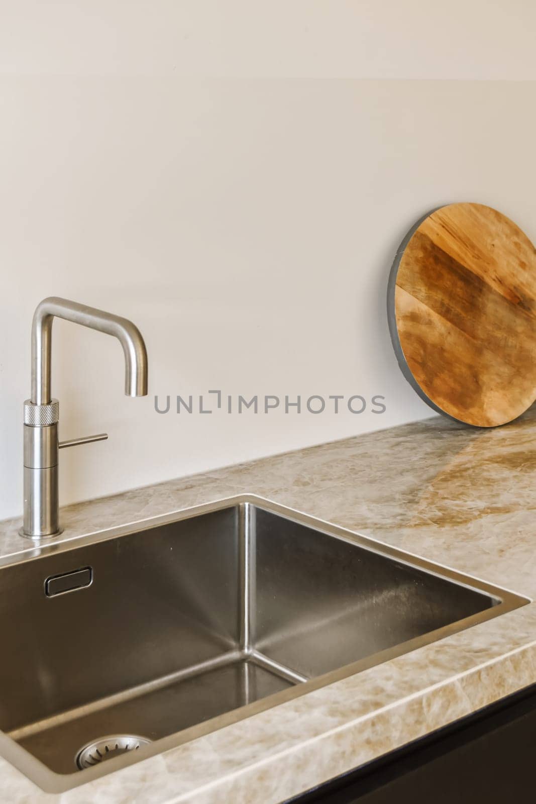 a kitchen sink with a wooden cutting board on the wall above it and a round mirror in the corner next to the sink