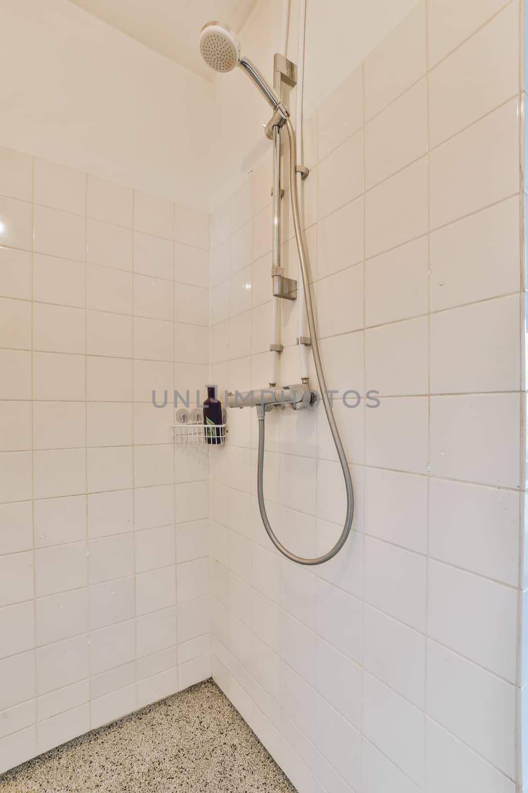 a shower in a white tiled bathroom with a by casamedia