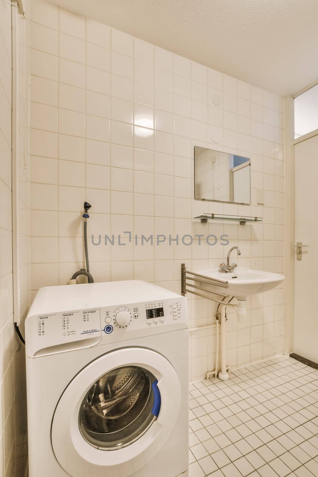 a laundry room with a washer and dryer in the corner, while it is white tile on the floor