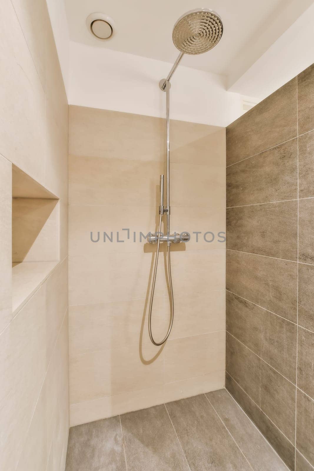 a shower with a shower head in a bathroom by casamedia