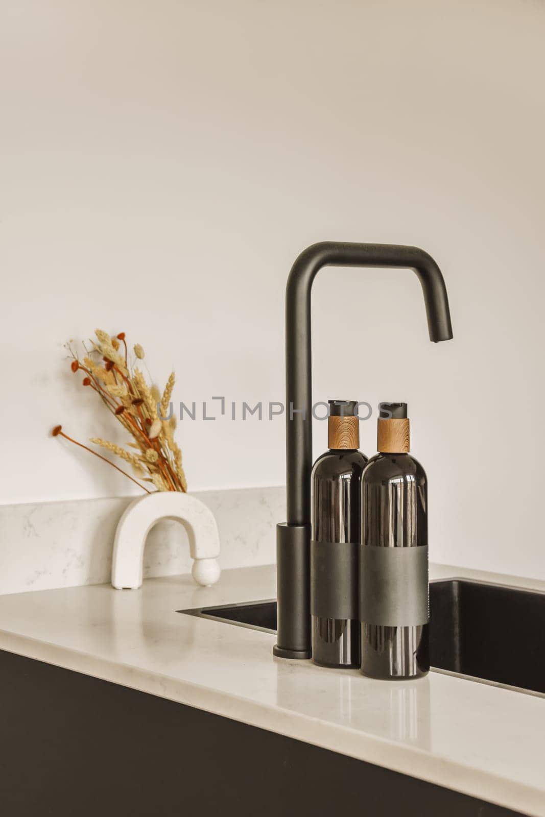 two bottles sitting on a kitchen counter with a tap by casamedia