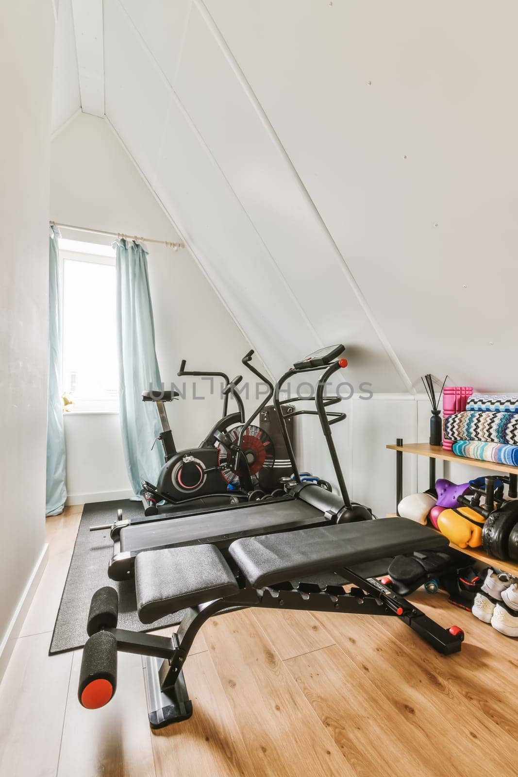 a gym room with an exercise bike and other equipment on the floor in front of the room is a window