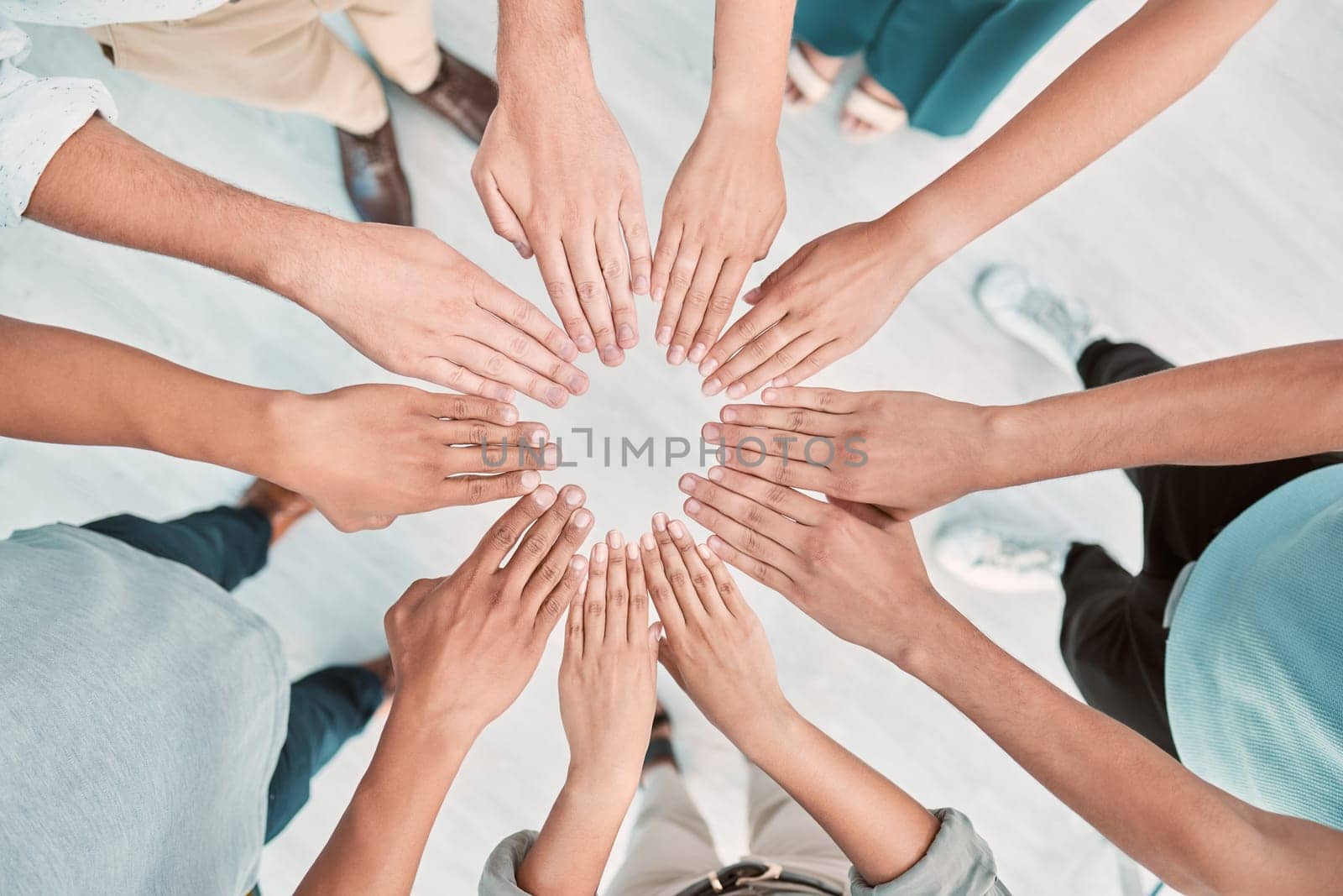 Hands, collaboration and motivation with a business team standing in a huddle or circle from above. Teamwork, goal and unity with a man and woman employee group together in the office for support by YuriArcurs