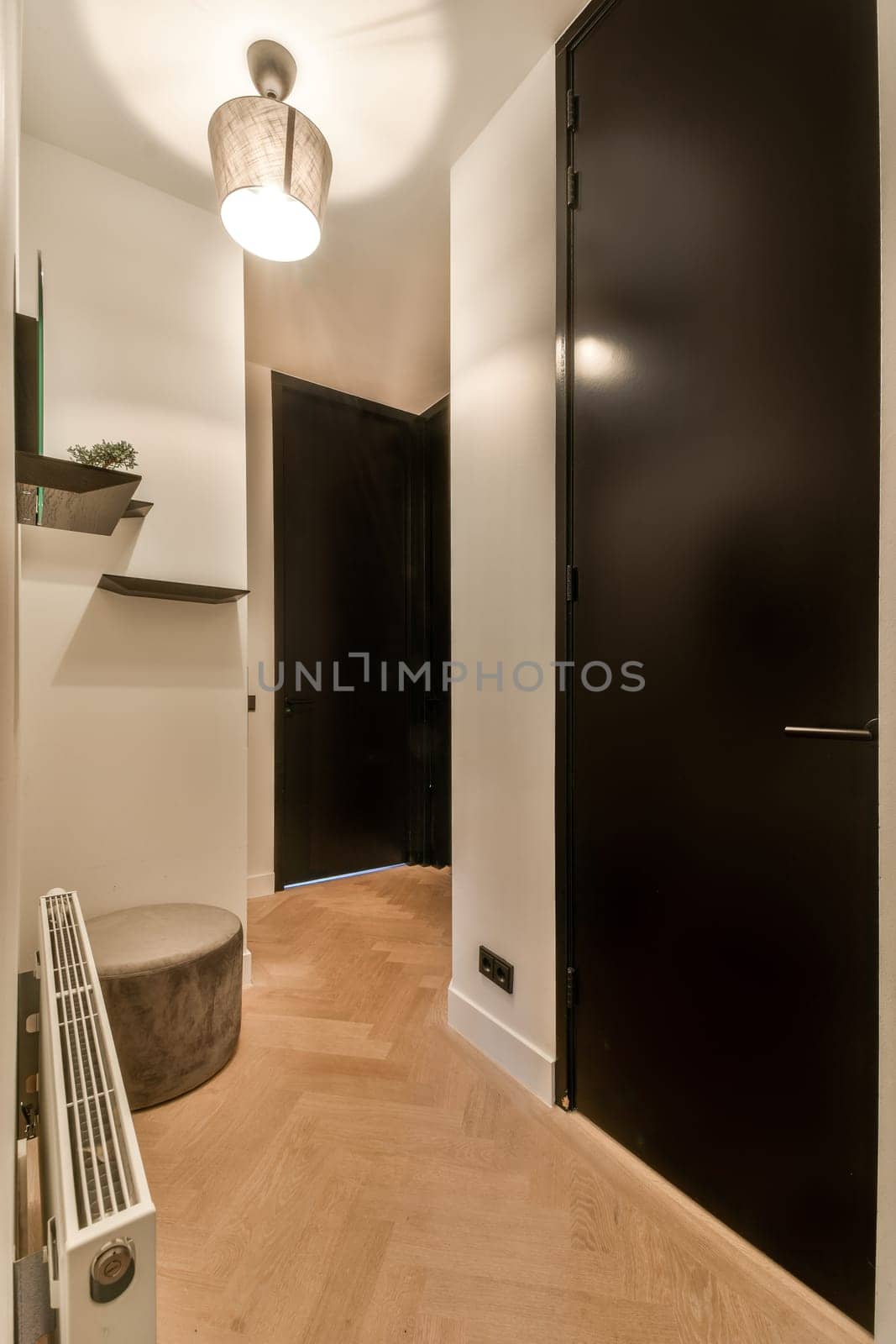 a small hallway with a black door and a stool by casamedia