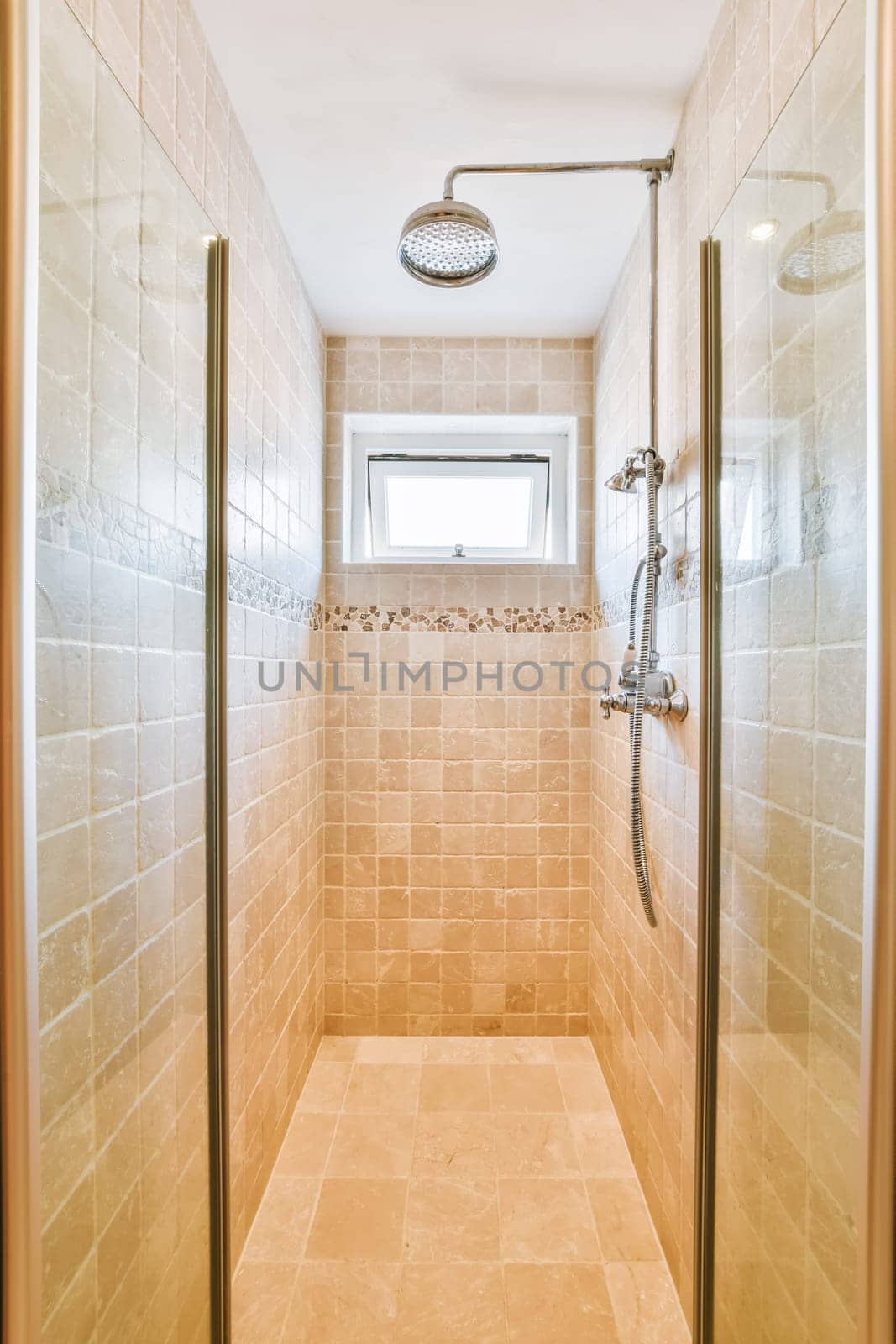 a walk in shower with tiled walls and beige tile on the floor, along with glass doors that allow access to the bathroom