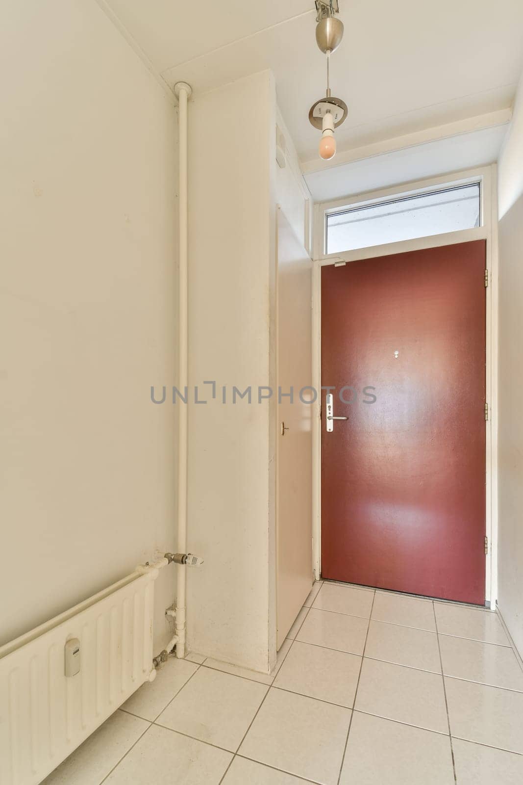 an empty room with a red door and white tiles on the floor in this photo is taken from the inside