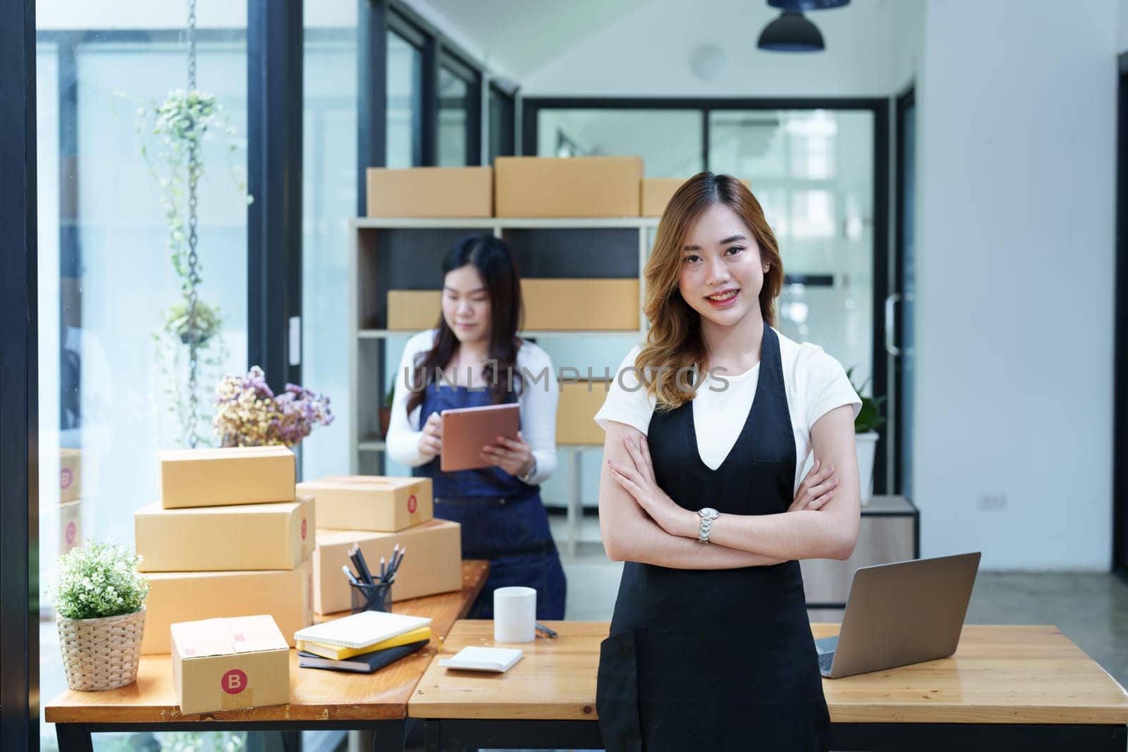 Starting small business entrepreneur of independent Asian woman smiling using computer laptop with cheerful success of online marketing package box items and SME delivery concept by Manastrong