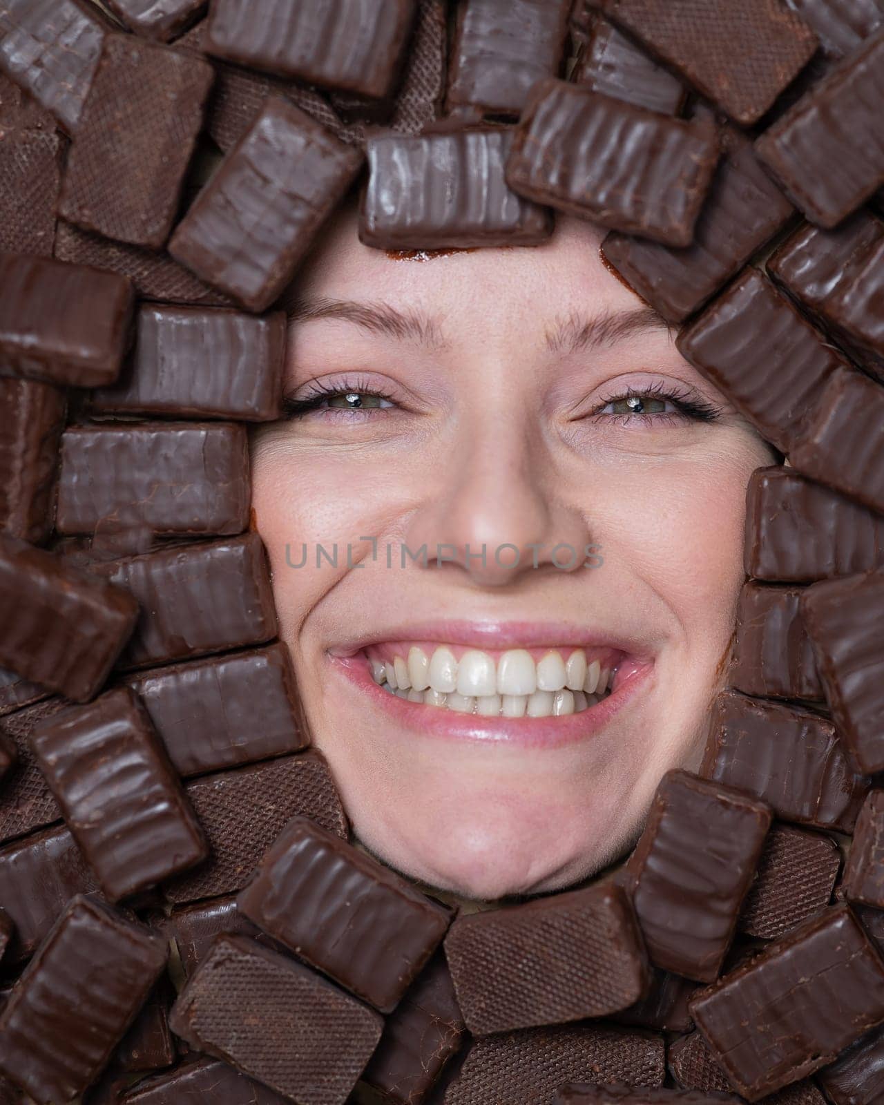 Face of caucasian woman surrounded by chocolates