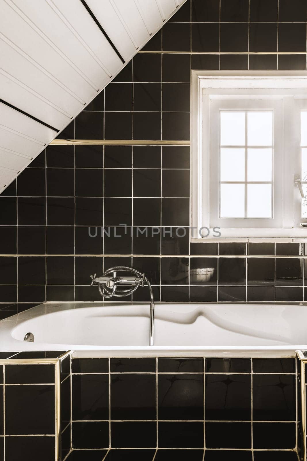 a white bath tub in a black tiled bathroom by casamedia