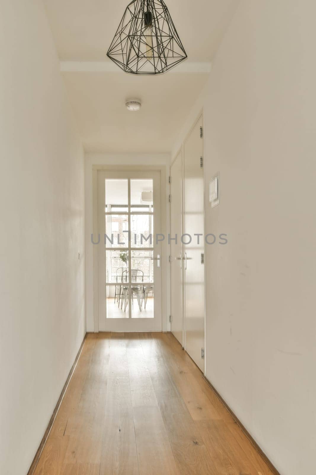 an empty room with white walls and wood flooring on either side, there is a light fixture in the ceiling