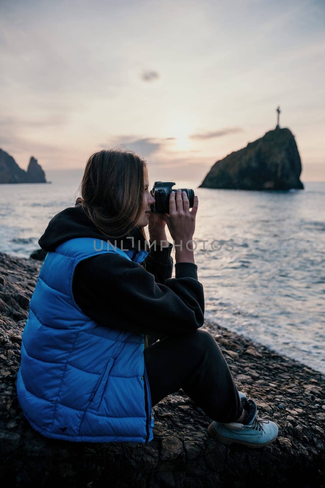 Woman travel sea. Happy tourist taking picture outdoors for memories. Woman traveler looks at the edge of the cliff on the sea bay of mountains, sharing travel adventure journey.