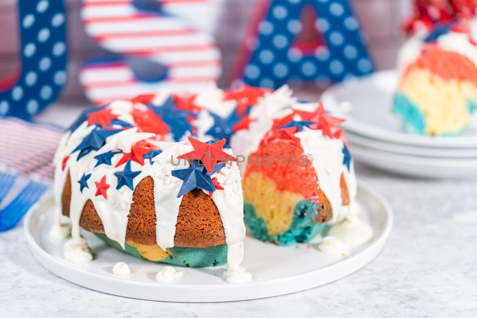 Slicing July 4th bundt cake covered with a vanilla glaze and decorated with chocolate stars.