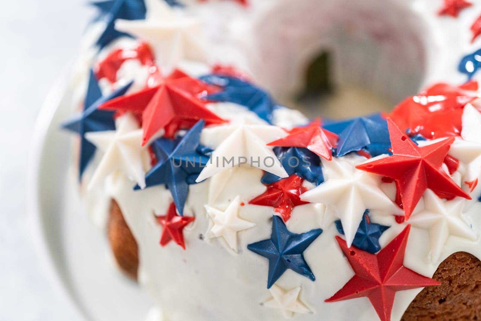 July 4th bundt cake covered with a vanilla glaze and decorated with chocolate stars on a white plate.