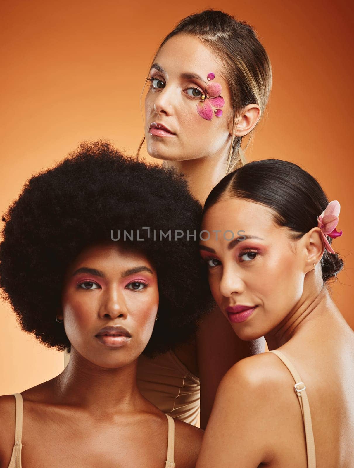 Portrait, flowers and women with makeup for spring against an orange mockup studio background. Face of model group with orchid plants for wellness, skincare beauty and body cosmetics for health.