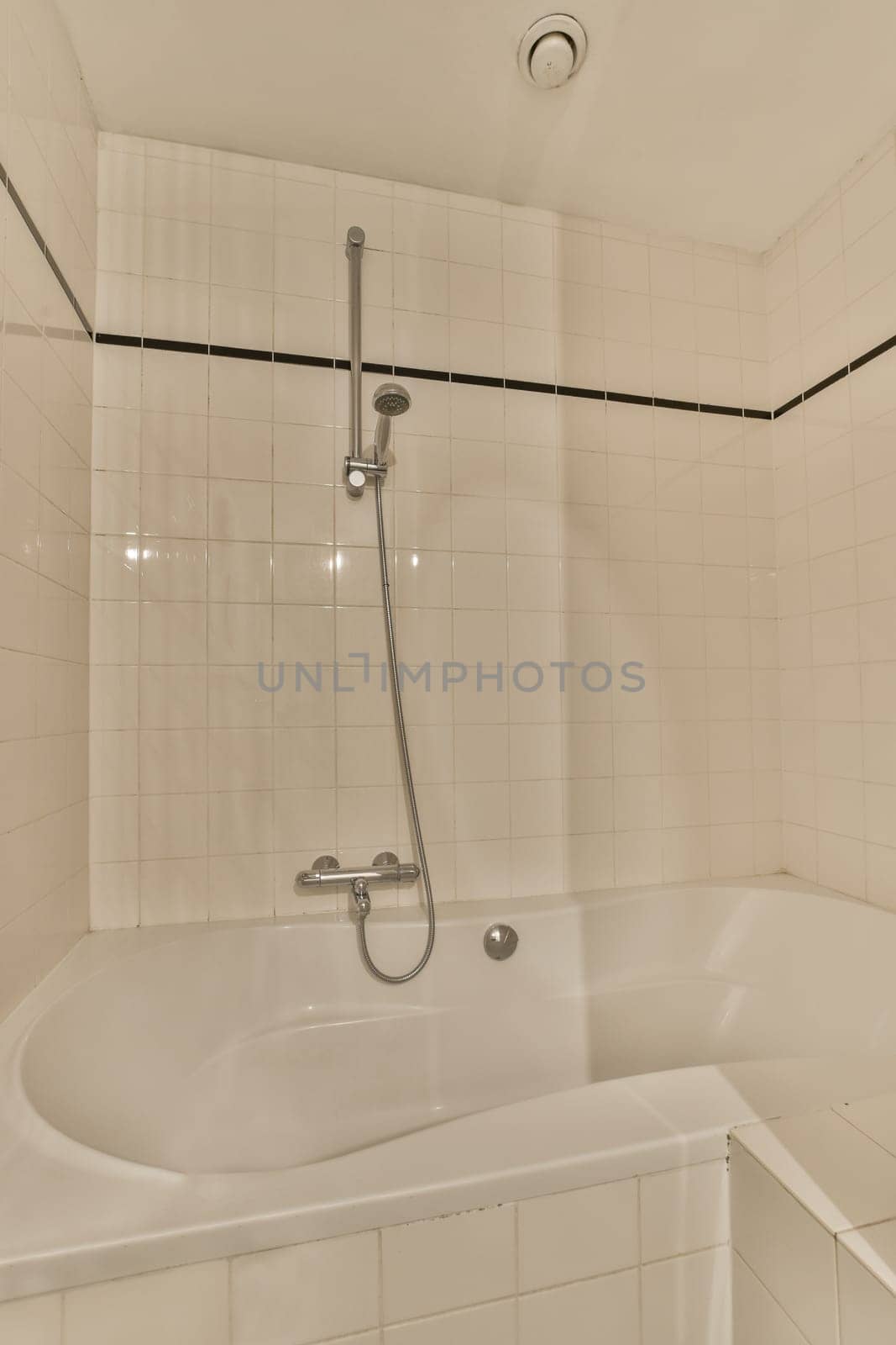 a bathtub in the corner of a bathroom with white tiles and black trim around the tub, which is attached to the shower