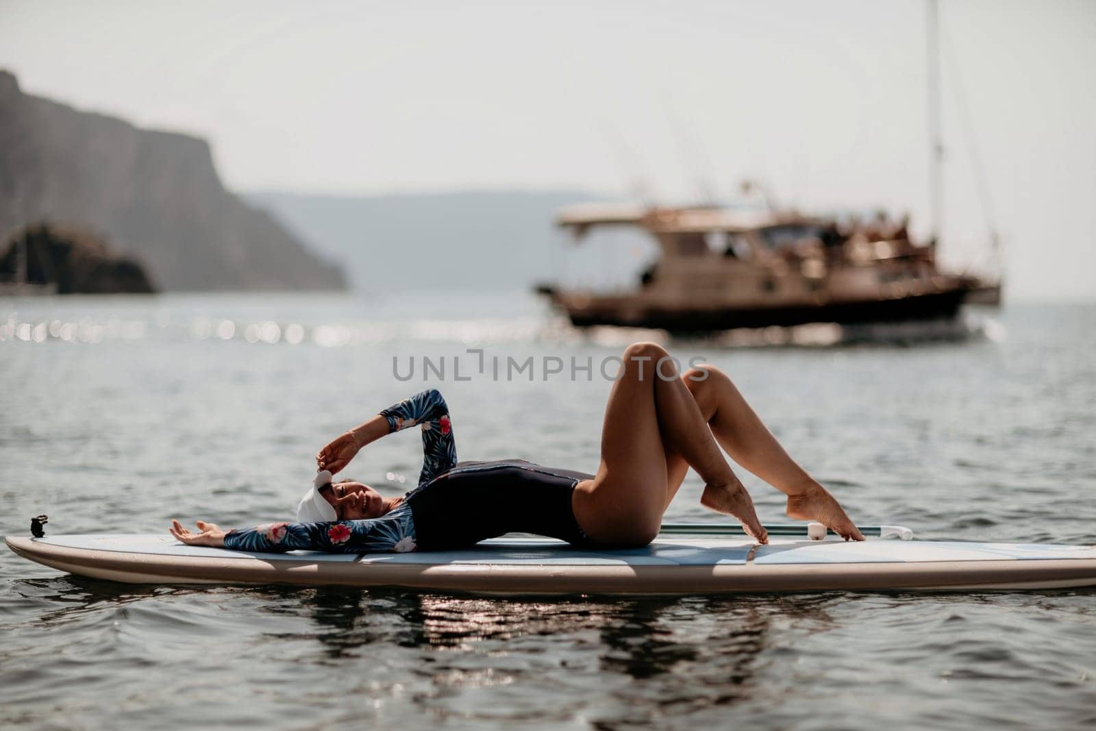 Woman sup yoga. Middle age sporty woman practising yoga pilates on paddle sup surfboard. Female stretching doing workout on sea water. Modern individual hipster outdoor summer sport activity