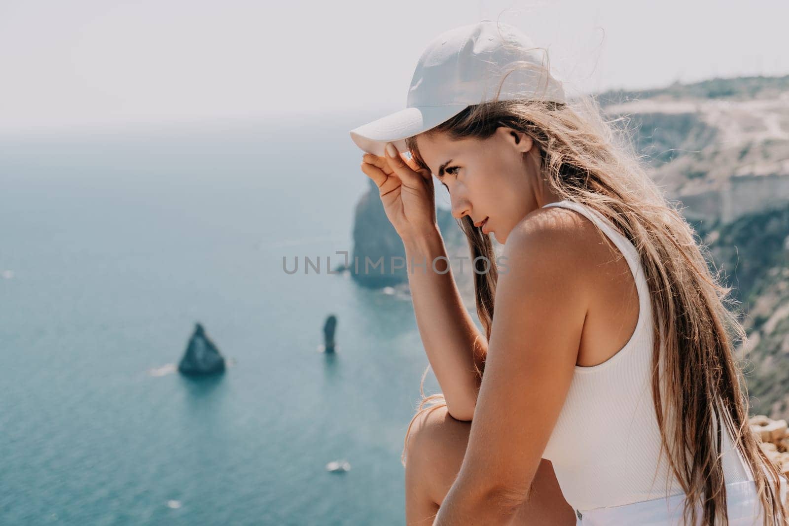 Woman travel sea. Young Happy woman in a long red dress posing on a beach near the sea on background of volcanic rocks, like in Iceland, sharing travel adventure journey