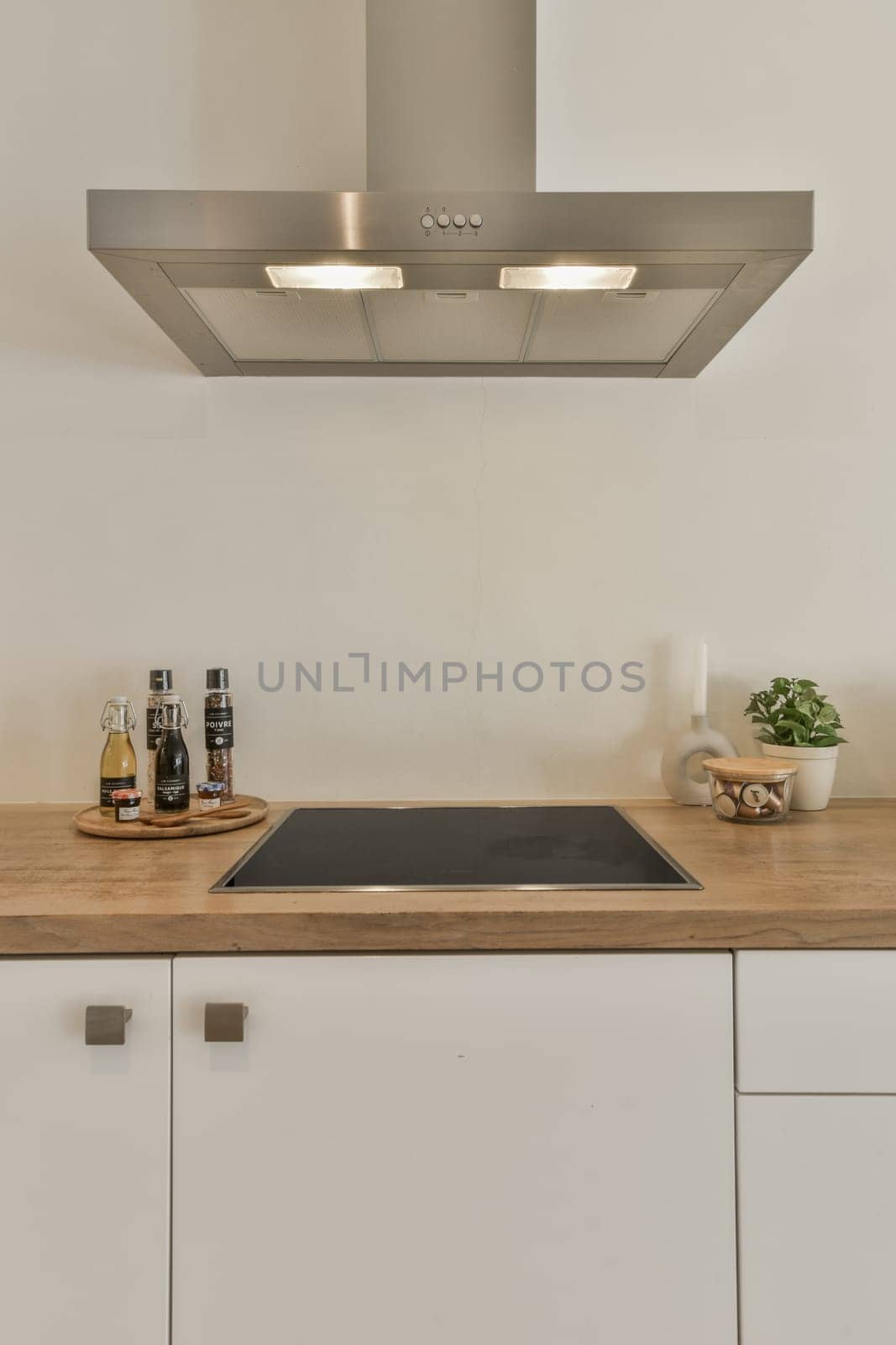 a kitchen with white cupboards and wood counter tops on the wall above it is a stainless hood over the stove