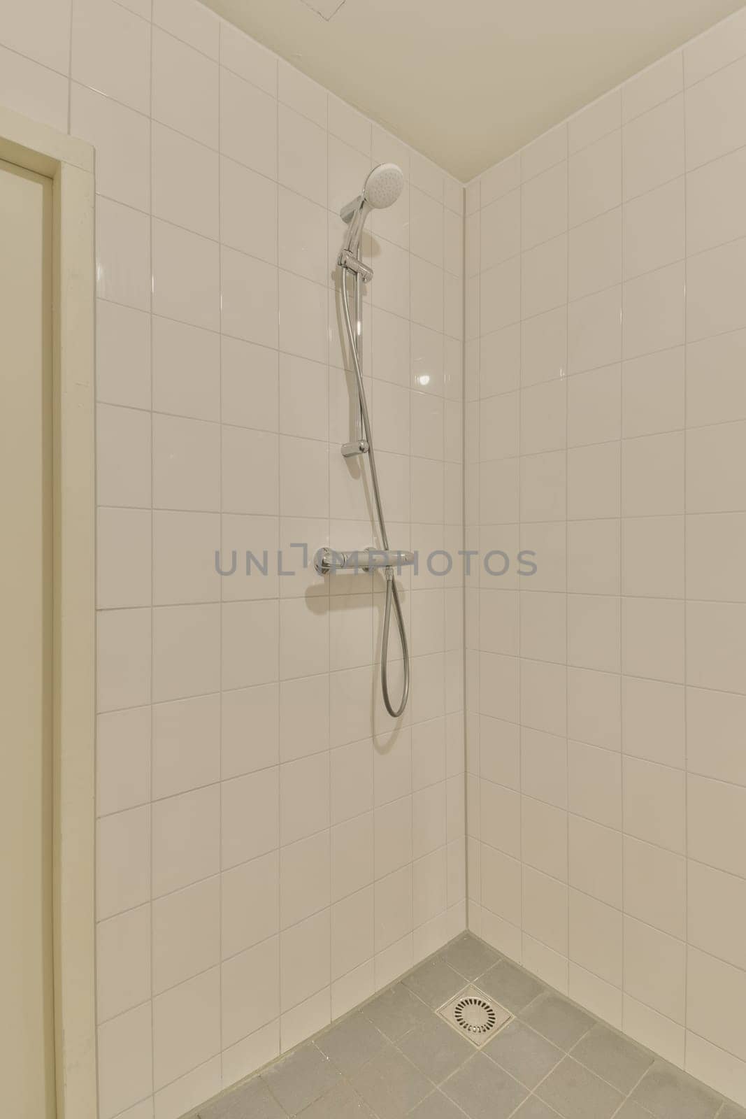 a shower in a white tiled bathroom with a by casamedia