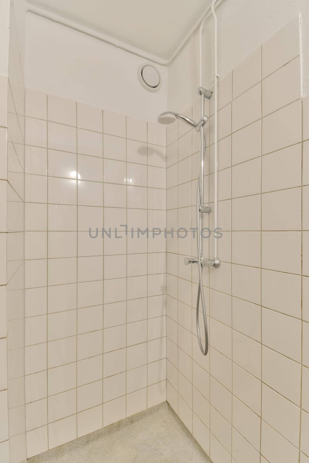 a bathroom with white tiles on the walls and shower head mounted to the wall in front of the bathtub