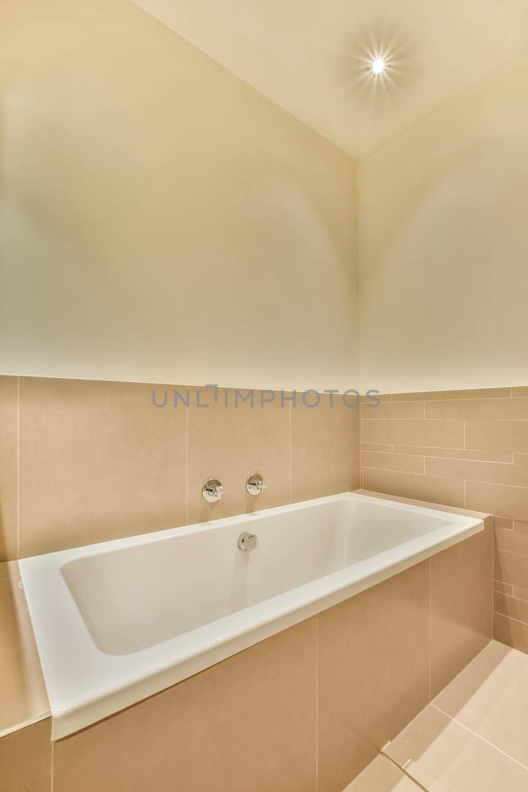 a bathtub in the corner of a room with beige tiles on the walls, and a white tub sitting next to it