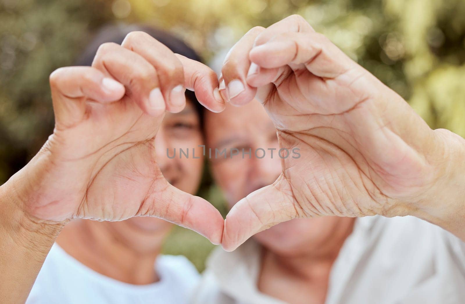 Heart hands, love and senior couple, happiness and kindness, trust and support in garden park. Closeup marriage, finger shape and celebrate care relationship, anniversary date and relax retirement by YuriArcurs