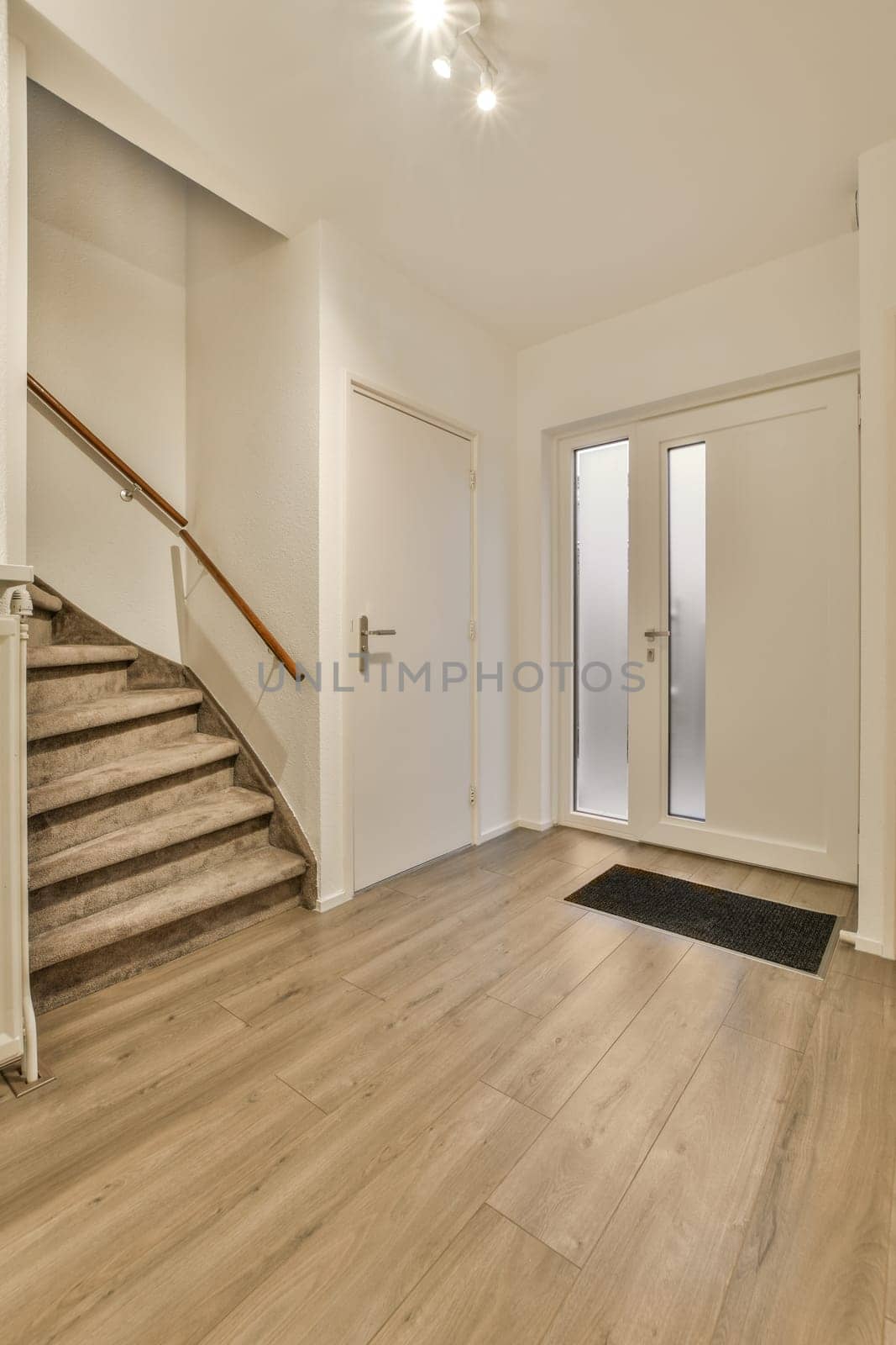 an empty living room with wood flooring and white walls, stairs leading up to the second floor in this home