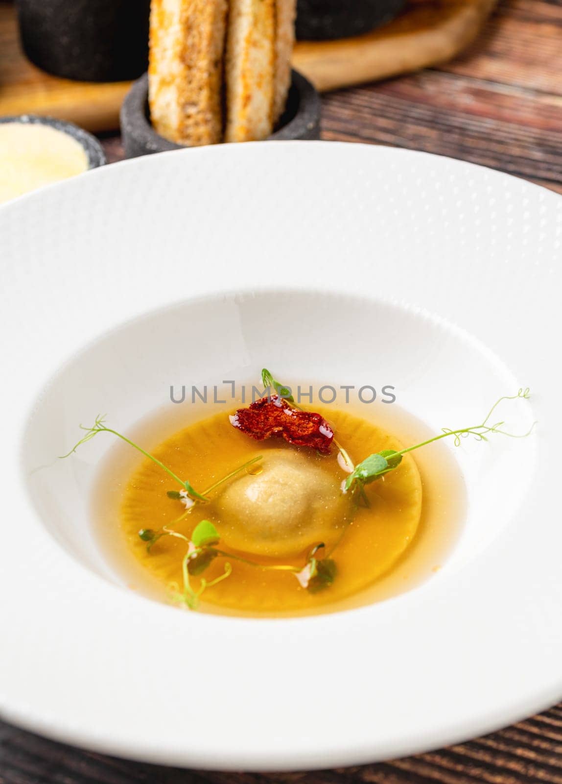 Ravioli consomme on a white porcelain plate. Healthy eating concept by Sonat