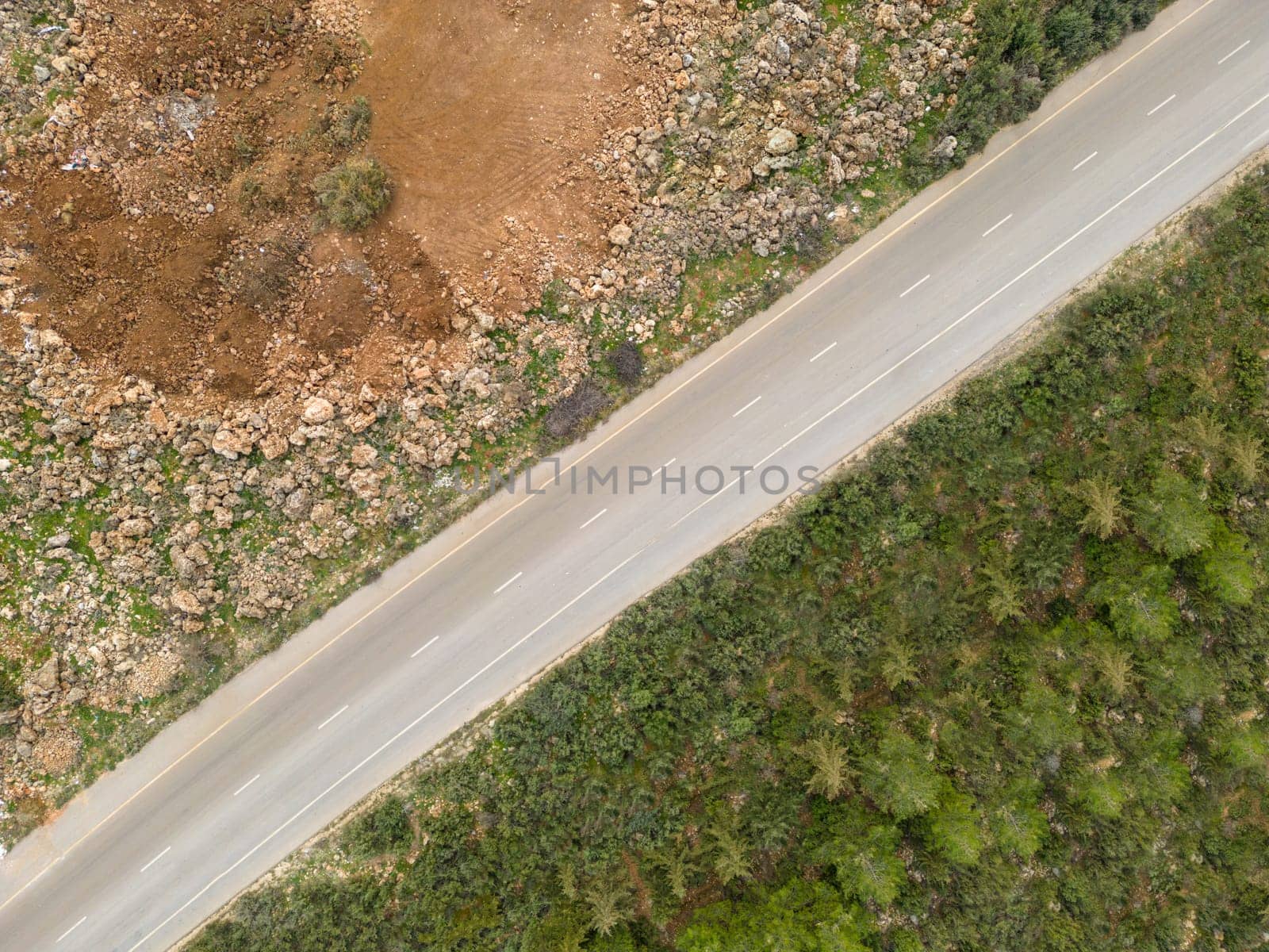 Aerial view of the road with trees on one side and dirt on the other
