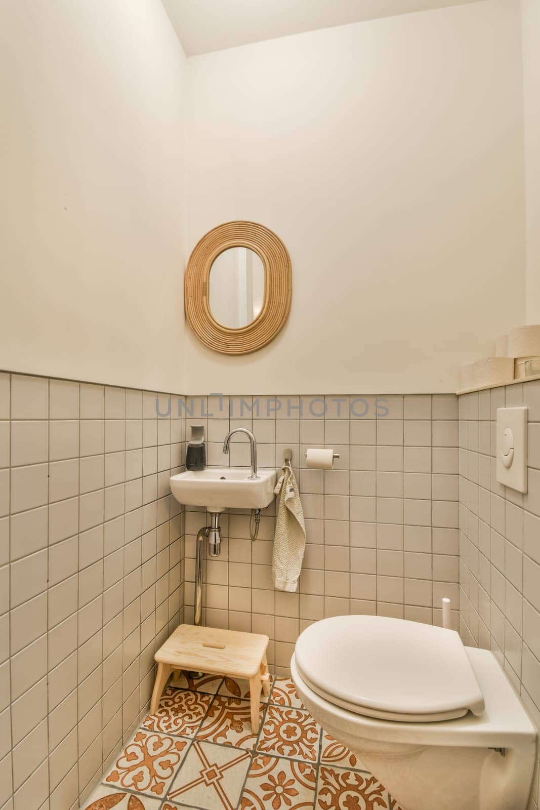 a bathroom with a toilet, sink and mirror on the wall behind it is a tiled floor that has an orange flower pattern