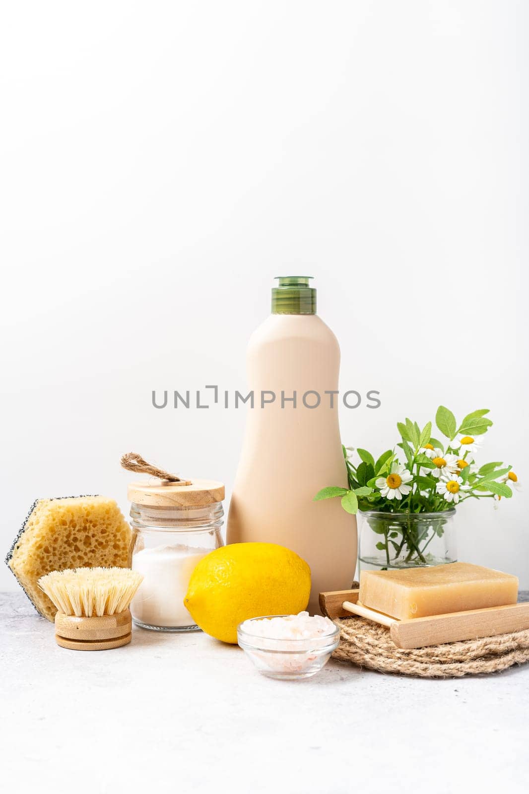 Eco friendly natural cleaners, jar with baking soda, dish brush, lemon, flowers, soap on white background. Organic ingredients for homemade cleans with mock up bottle. Zero waste concept, copy space by Ostanina