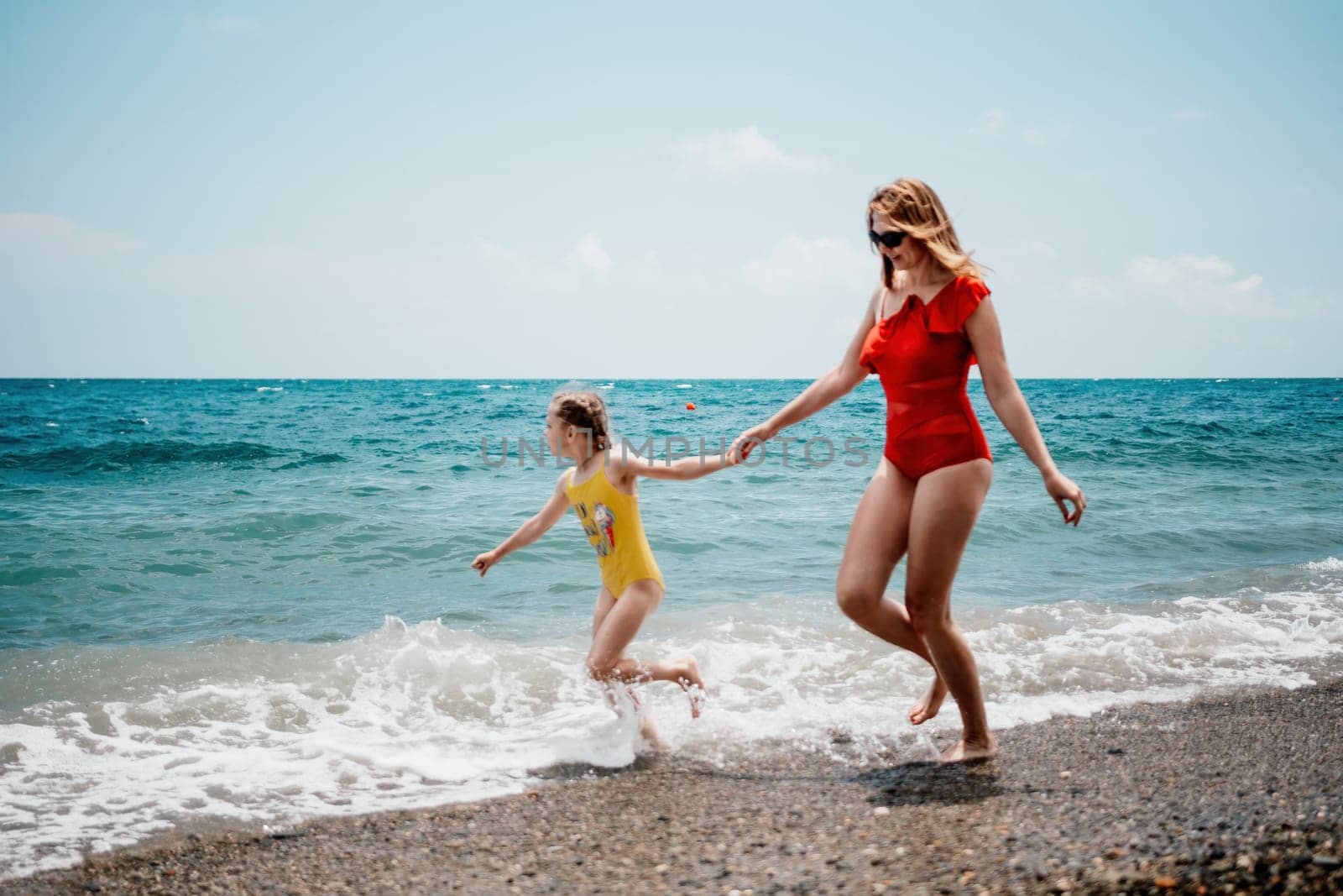 Happy loving family mother and daughter having fun together on the beach. Mum playing with her kid in holiday vacation next to the ocean - Family lifestyle and love concept.
