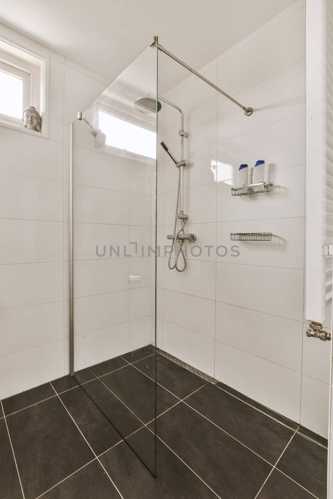 a modern bathroom with black tile flooring and white tiles on the walls, along with a walk - in shower