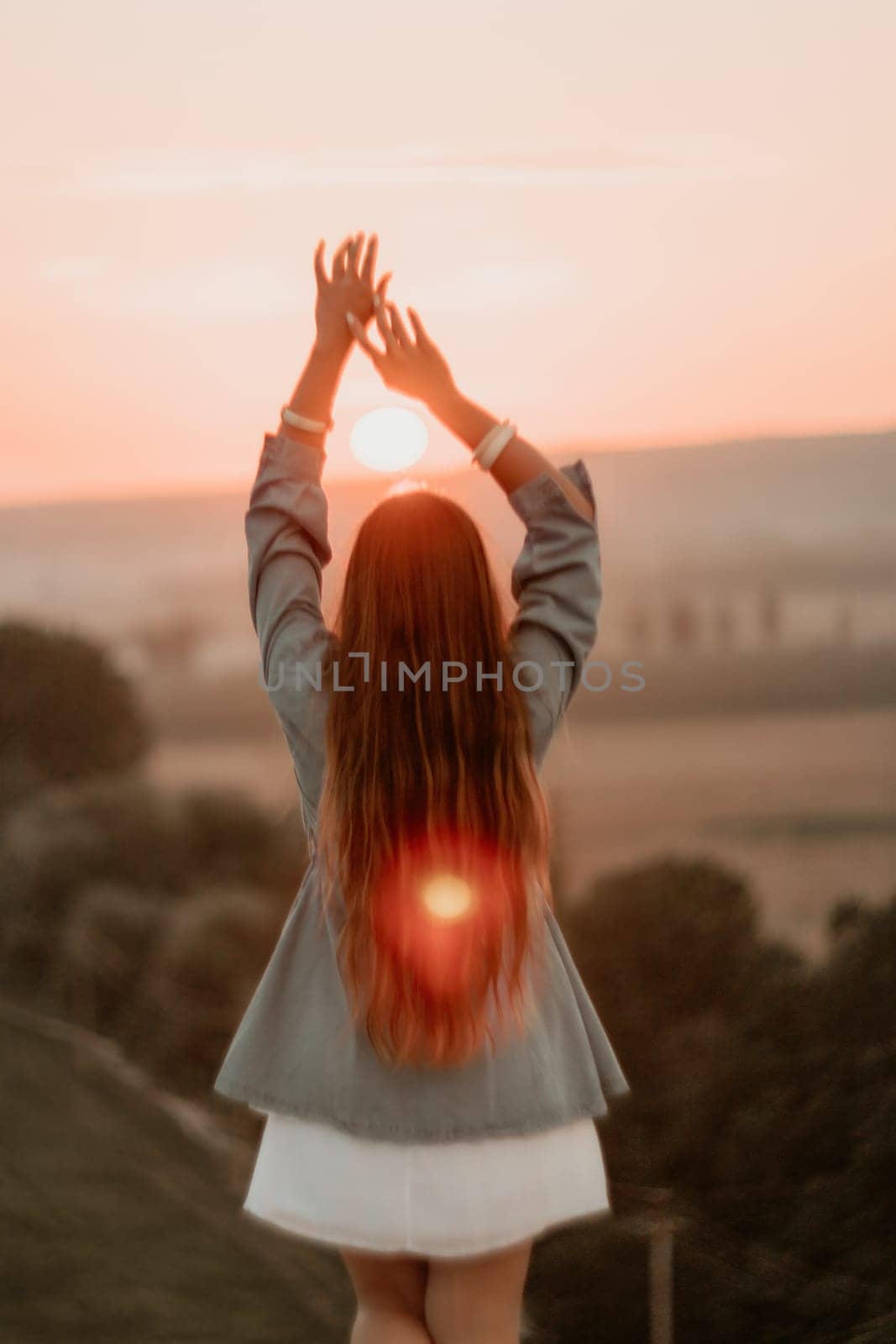 Romantic beautiful bride in white dress posing with sea and mountains in background. Stylish bride standing back on beautiful landscape of sea and mountains on sunset