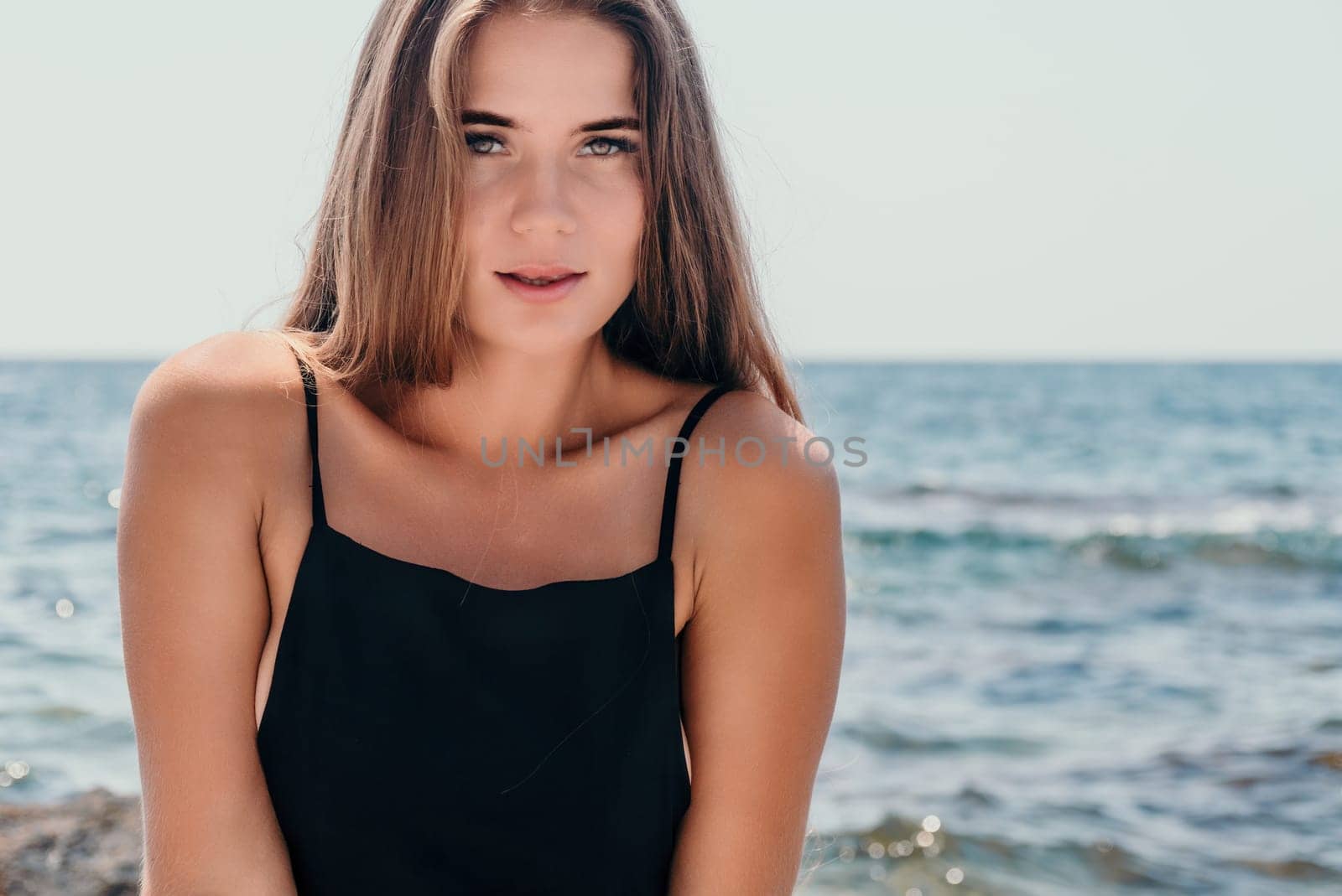 Woman travel sea. Young Happy woman in a long red dress posing on a beach near the sea on background of volcanic rocks, like in Iceland, sharing travel adventure journey