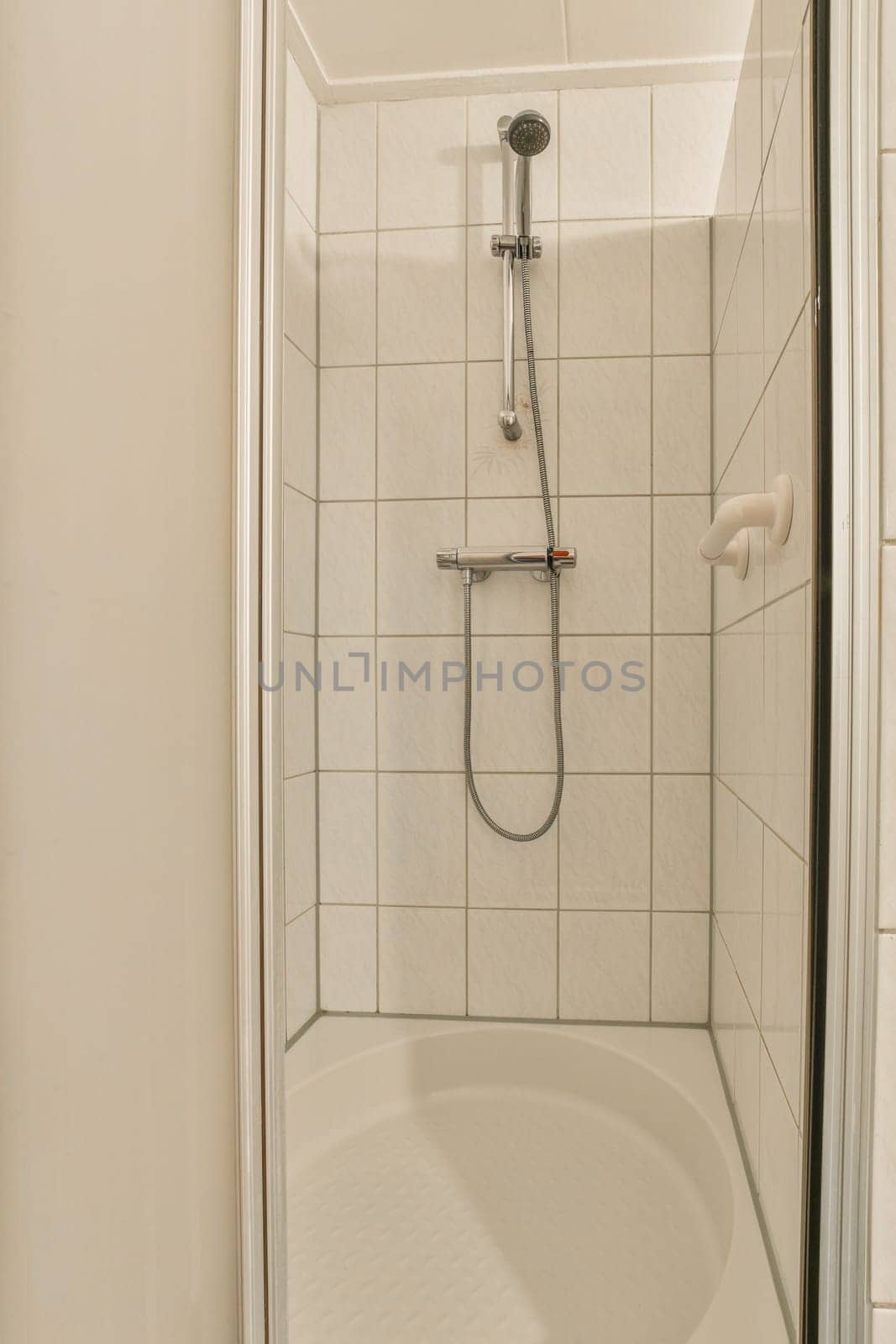 a shower in a white tiled bathroom with a by casamedia