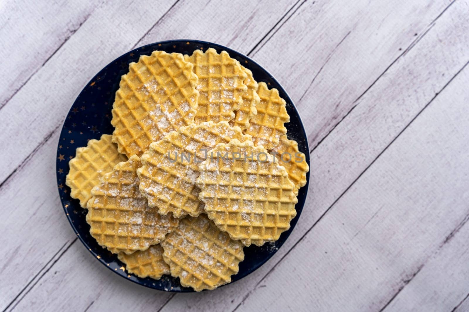 sweet delicious crispy waffles sprinkled with powdered sugar on a plate by the window. Breakfast. Top view