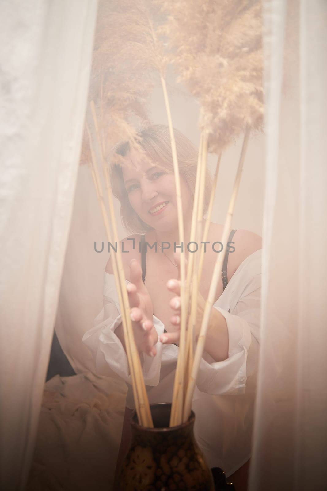 Portrait of sexual body positive adult lady woman in intimate in tender space indoors in a bedroom. Plump girl poses in black underwear and white shirt during boudoir style photo shoot