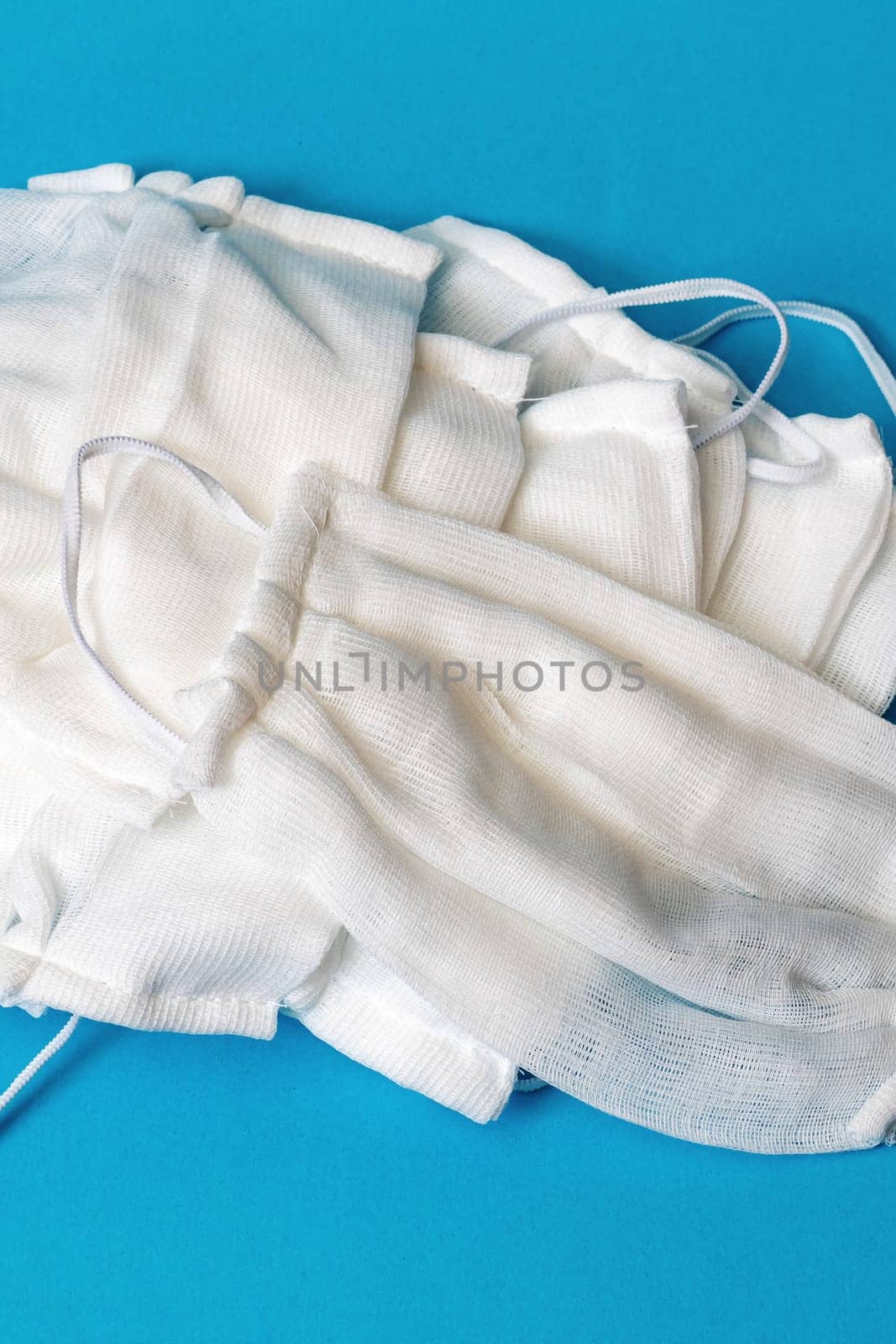 Pile of gauze medical masks on a blue background close up