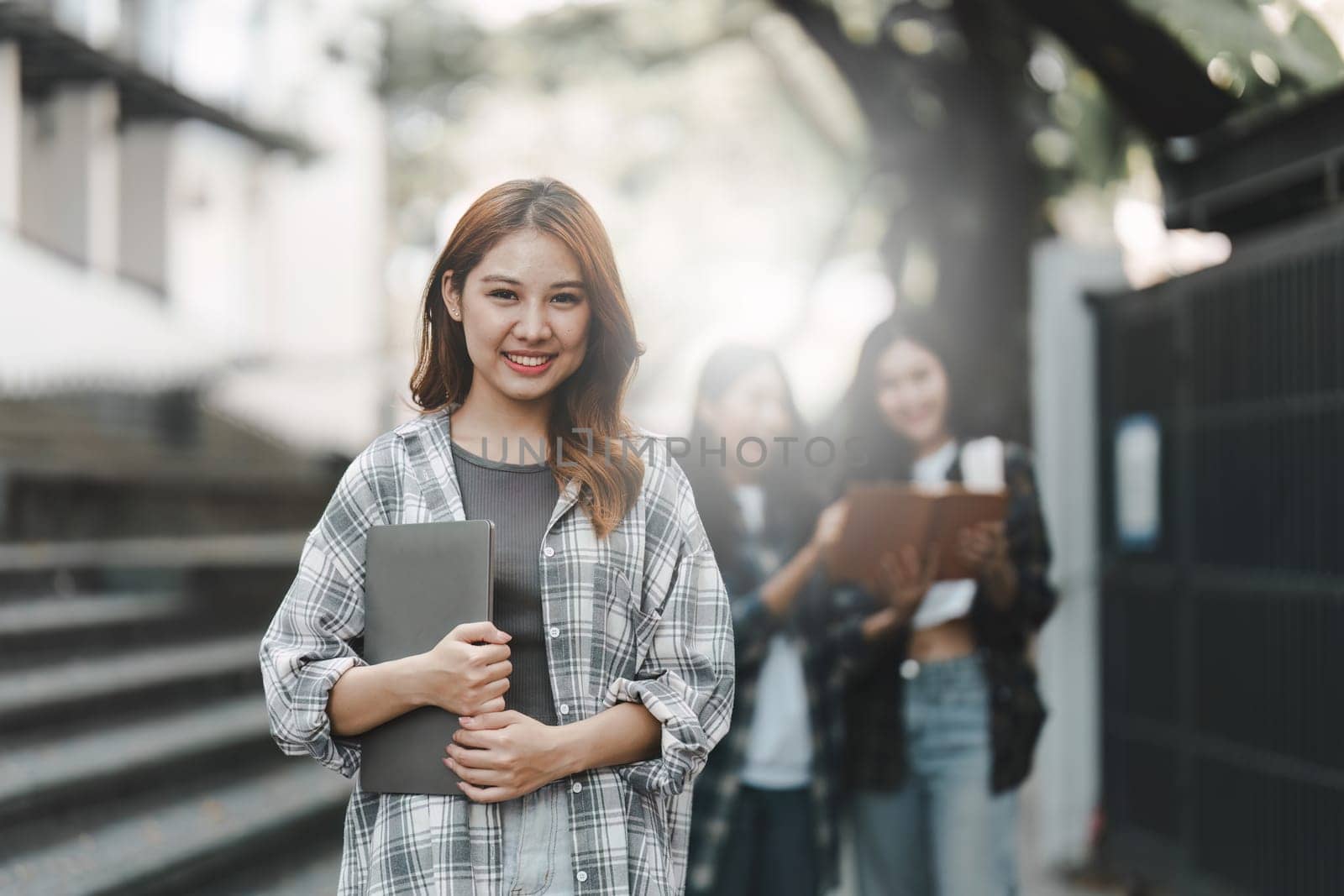 Young Asian woman college student with friends at outdoors. College student working on the college campus, education, school, study by itchaznong