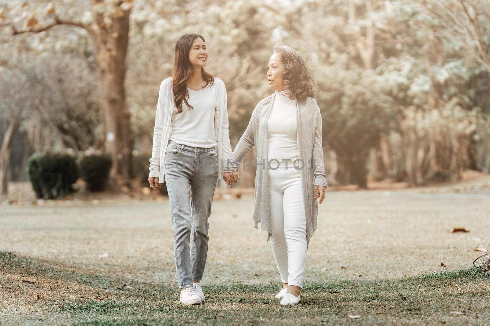 Close up of Adult daughter holding her elderly mother hand with love and walk together.
