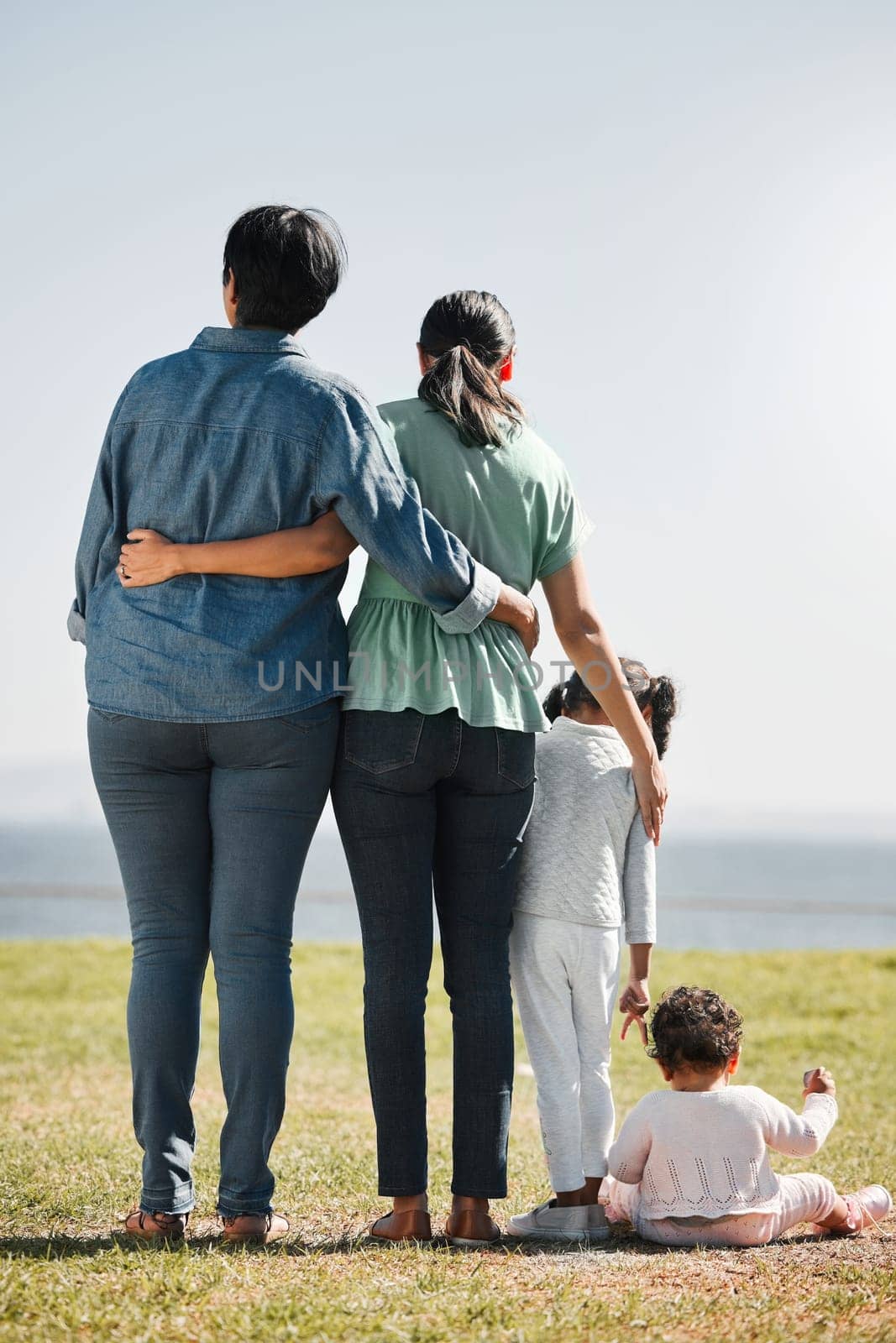 Park, nature and back view of family on grass outdoors with relatives spending quality time together. Love, support and caring grandma, mom and girl with baby bonding together with scenic ocean view
