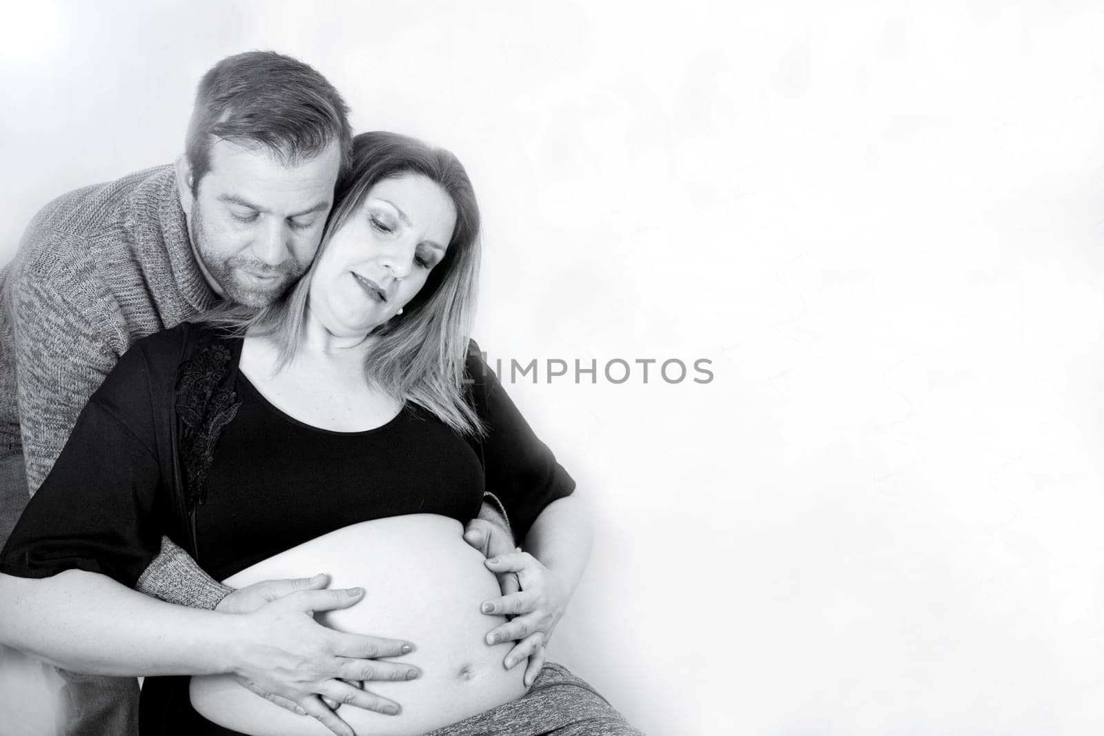 Eight months pregnant woman and dad hugging her. Happy expression