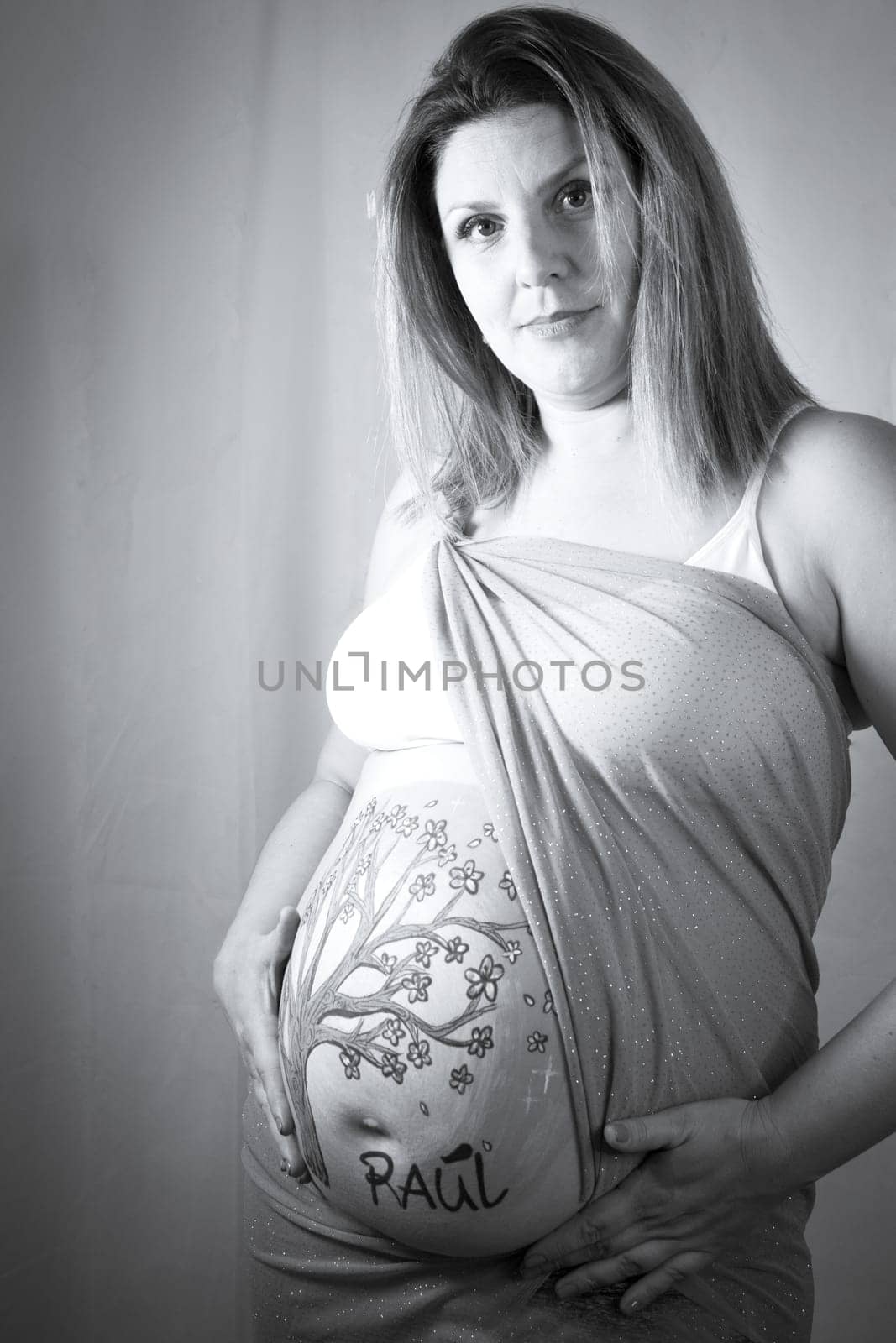 Eight months pregnant woman with bright dress and drawing on her belly. No copy space